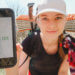 the trek logo appears on phone screen that is held up by a girl in thruhiking gear